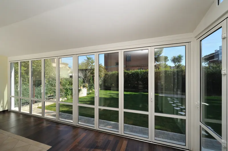Long run of white-framed Panda® folding doors along a living room facing a lawn