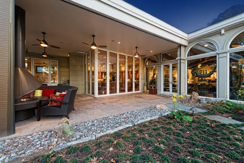 Panda® sliding glass walls opening a residence onto a stone courtyard at dusk