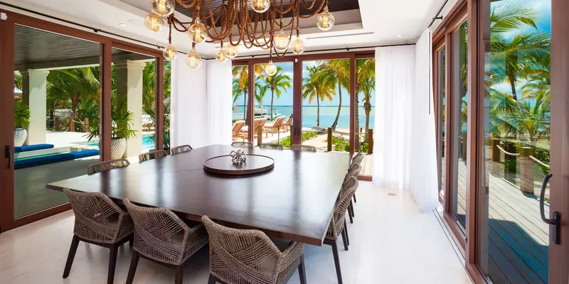 Dining room opened to a pool deck and the ocean through Panda® lift and slide doors at Kempa Kai