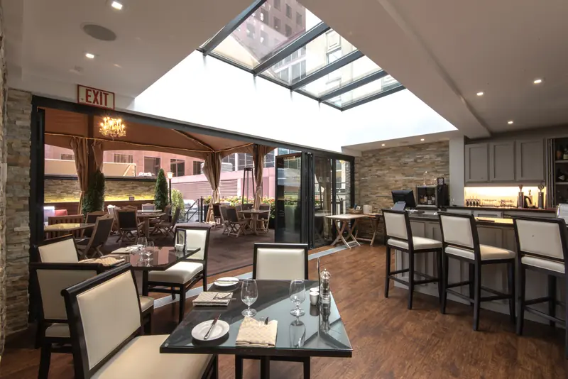Panda® folding doors opening a restaurant bar onto a covered patio under a skylight at The National Club