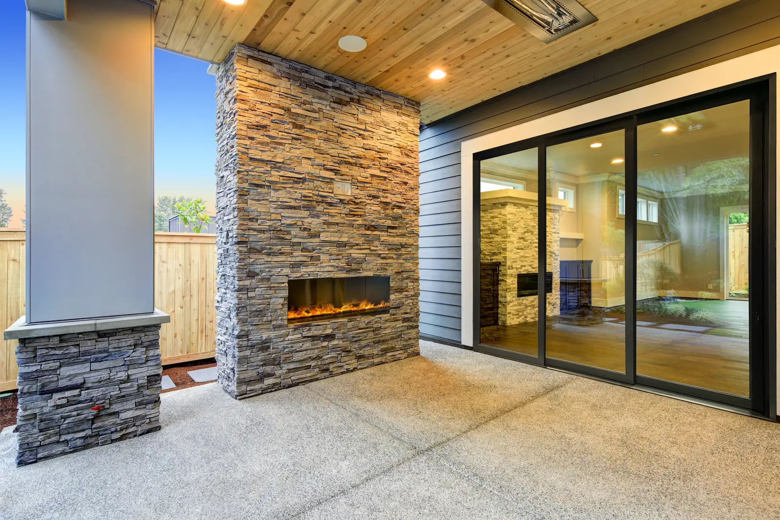 Black Panda® PandaSelect LTS.30 lift and slide doors beside a stacked-stone outdoor fireplace