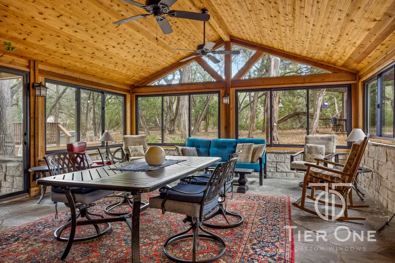 Bronze window bank wrapping an enclosed porch under a cedar plank ceiling