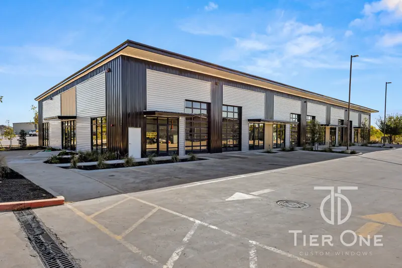 Corner of a new flex building with dark-framed storefront at every suite