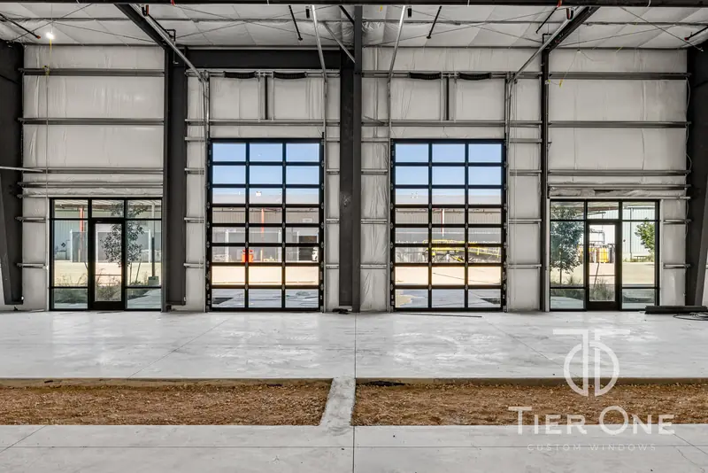 Interior of a warehouse bay lit through glass overhead doors and storefront
