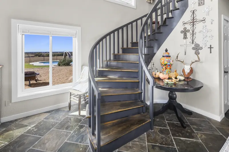 White sliding window beside a spiral staircase in the entry