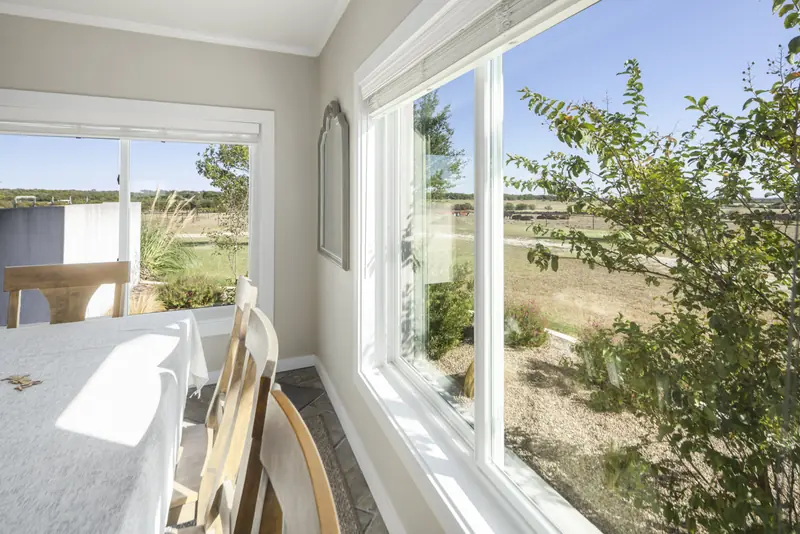 White sliding window beside the dining table looking onto the ranch