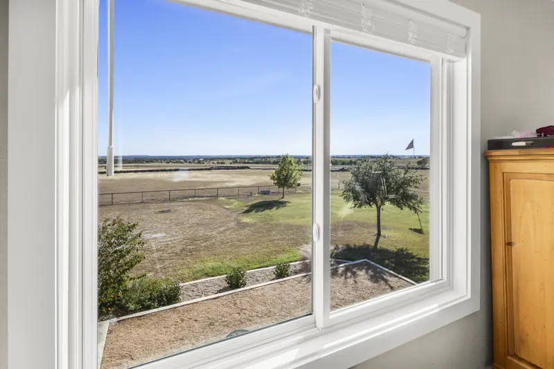 White sliding window looking onto the yard and flagpole