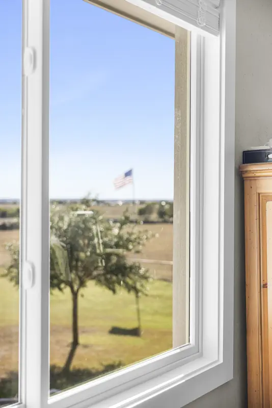 Tall white sliding window beside a wooden armoire