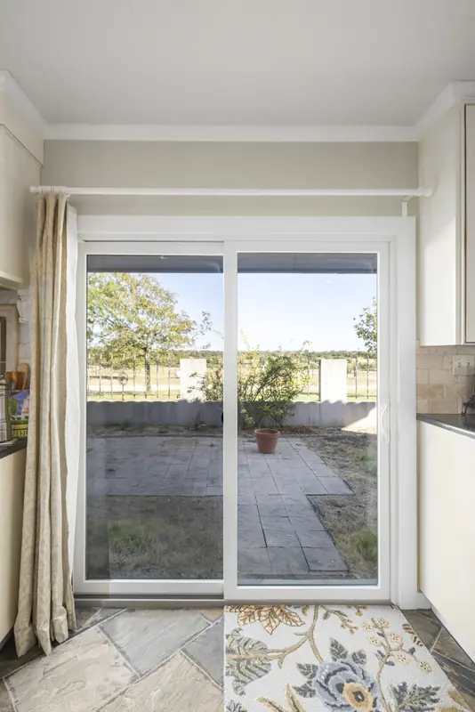 White sliding patio door opening onto a stone patio