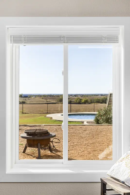 White sliding window looking onto the pool and fire pit