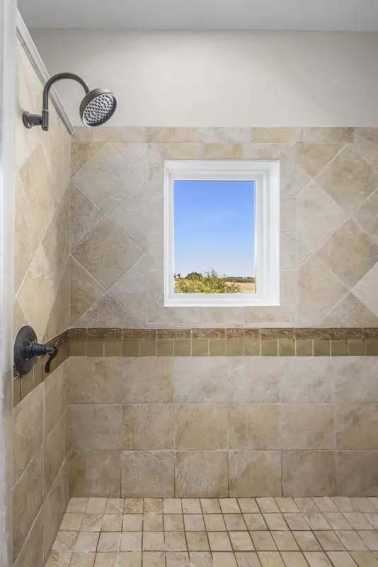 Small white-framed window set high in a tiled shower