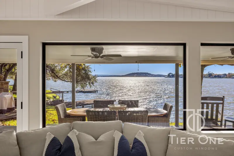 Black-framed picture window looking over the covered deck to the lake