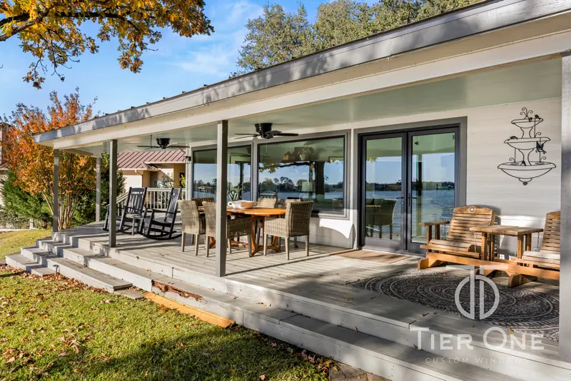 Covered deck lined with windows and sliding doors facing the lake