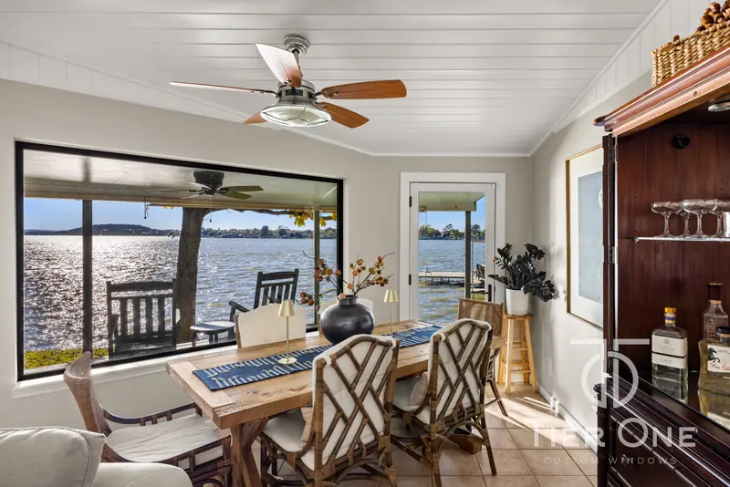 Wide black-framed window over the water beside a dining table