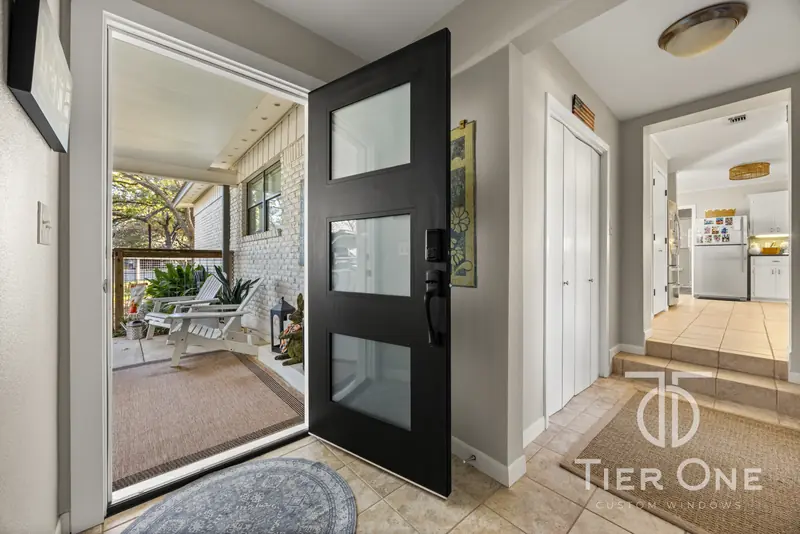 Black three-lite entry door open onto the screened front porch