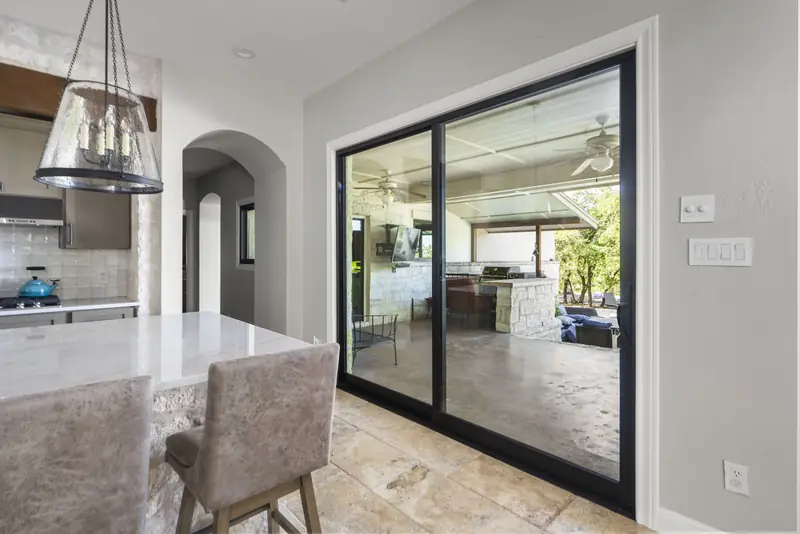Black sliding glass door from the kitchen to a covered outdoor kitchen