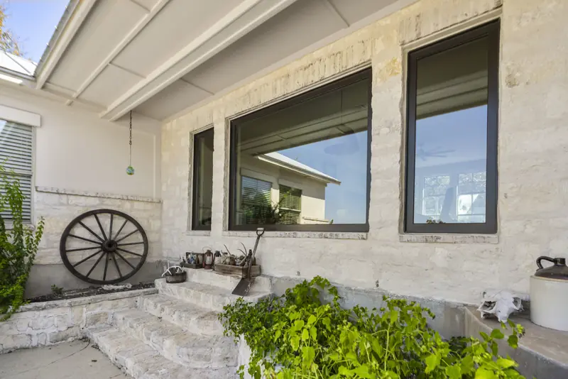 Black-framed windows set in a white limestone wall under the porch