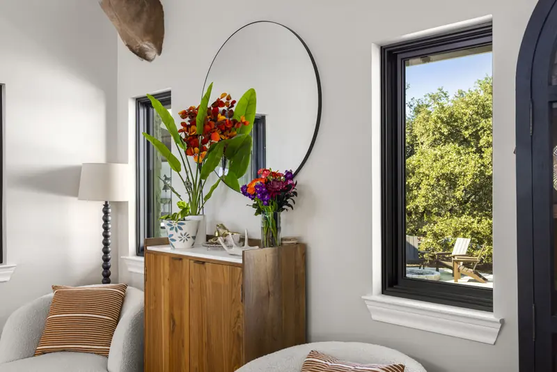 Tall black-framed window framing the oaks