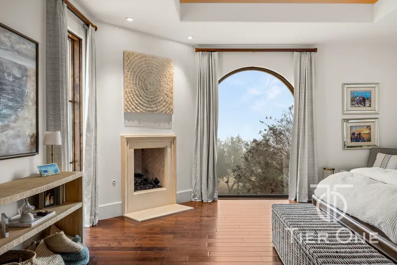 Arched window beside the fireplace in a primary bedroom