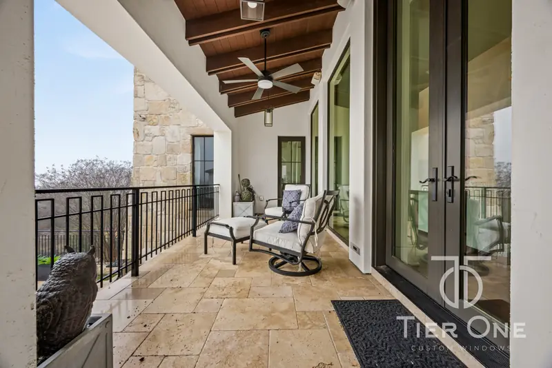 Row of French doors opening onto a travertine balcony with an iron railing