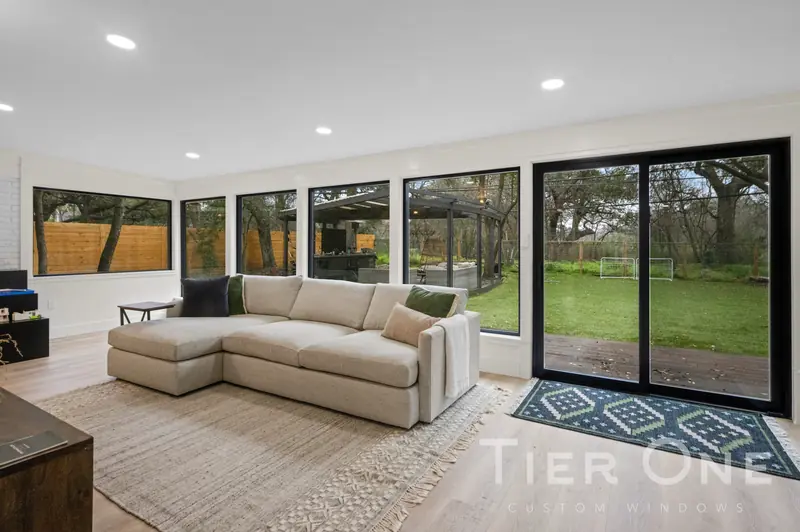 Sunroom wrapped in black-framed windows with a sliding door onto the lawn