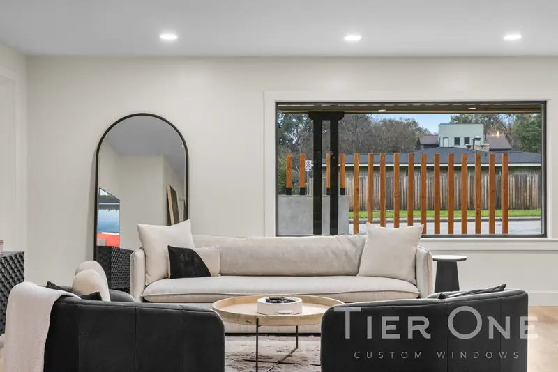 Living room with a wide black-framed picture window to the front yard