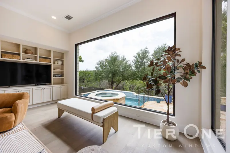 Black-framed picture window looking over a pool and spa