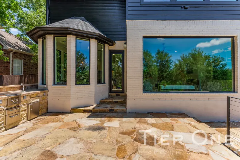 Painted brick rear elevation with a bay window and a large picture window over a stone patio