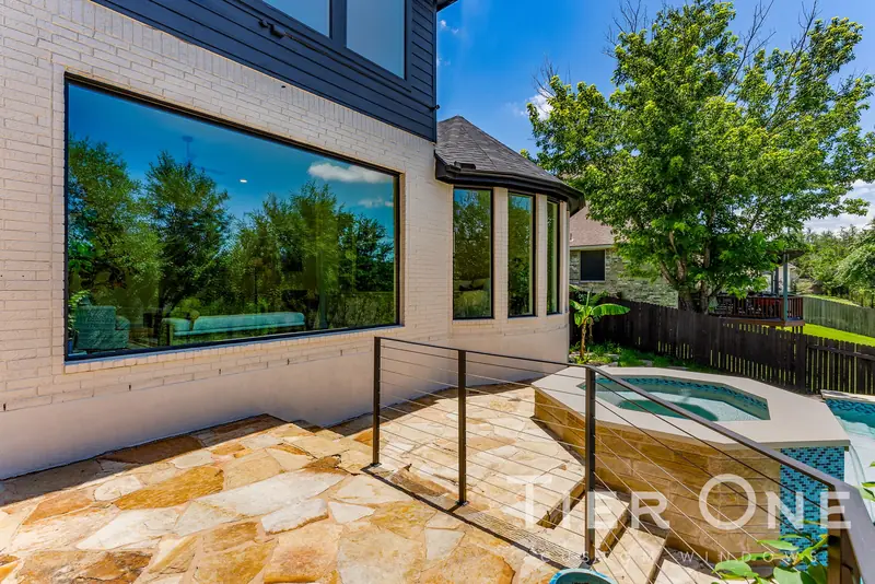 Large black-framed picture window reflecting the trees above a spa
