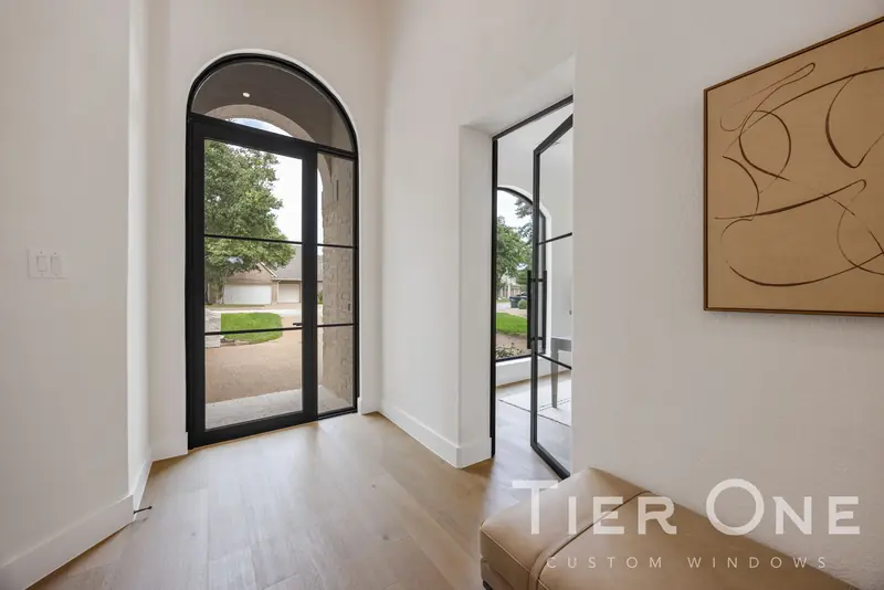 Arched steel-look entry door and a glass office door off the foyer
