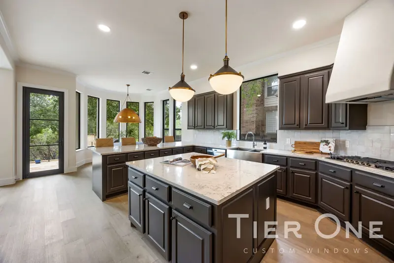 Kitchen island with a curved run of tall black-framed windows beyond
