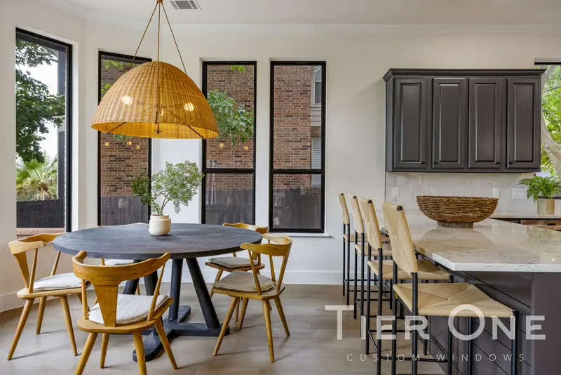 Tall black-framed windows around a round breakfast table