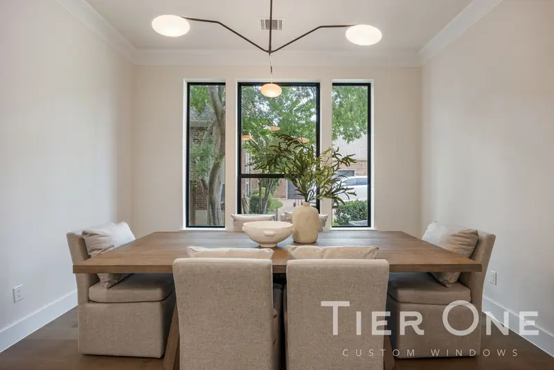 Three tall black-framed windows behind a dining table