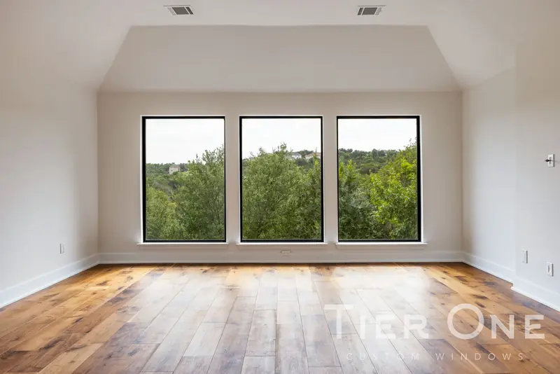 Three black-framed windows side by side in an empty upstairs room