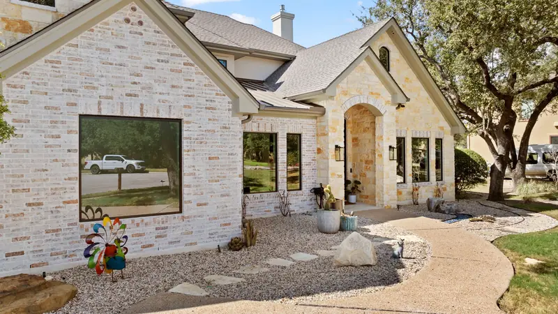 Front of a stone and brick home with a large picture window beside the arched entry