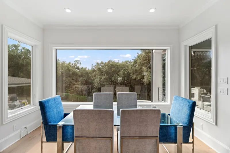 Picture window flanked by two windows around a glass dining table
