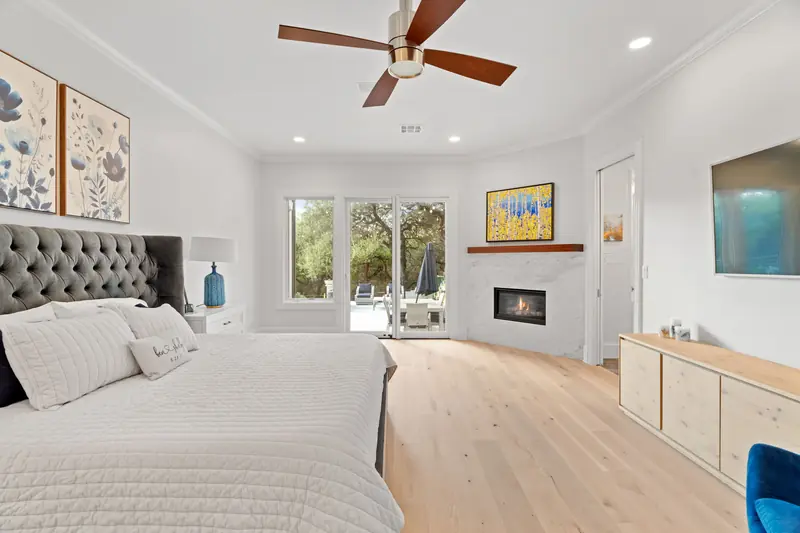 Primary bedroom with a window and glass patio door beside the fireplace