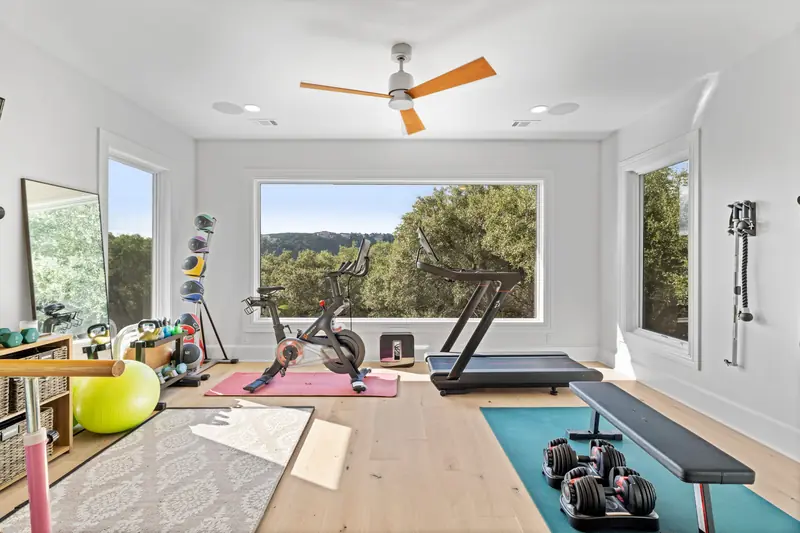 Home gym with a wide picture window over the hills