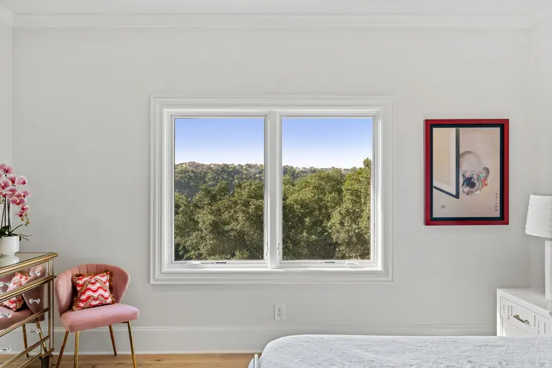 White-framed window pair looking out over wooded hills