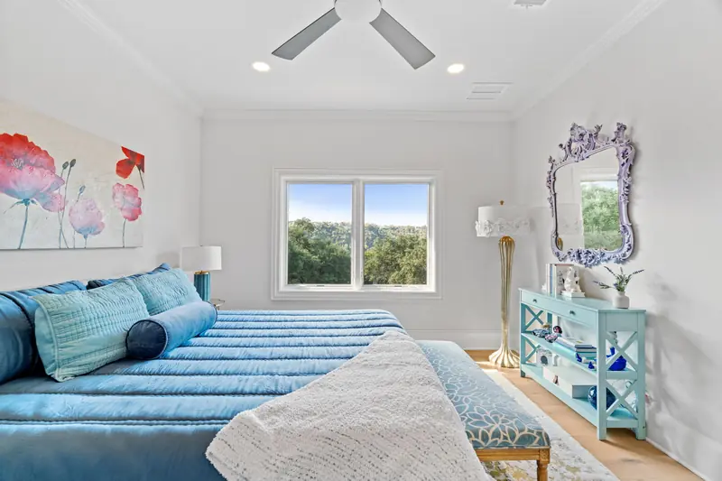 Guest bedroom with a white-framed window pair over the treetops