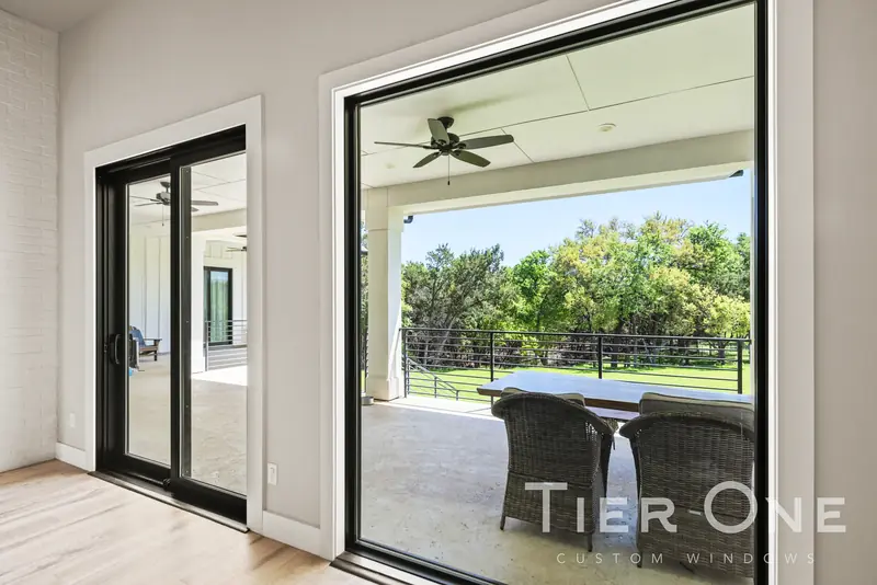 Black sliding door beside a large picture window onto the porch