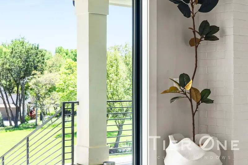 Tall black-framed window looking past a porch column to the lawn