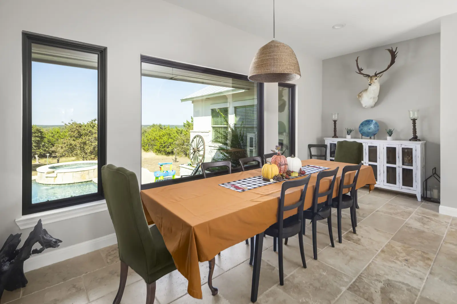 Black-framed picture window in a dining room looking out over a pool and hill country