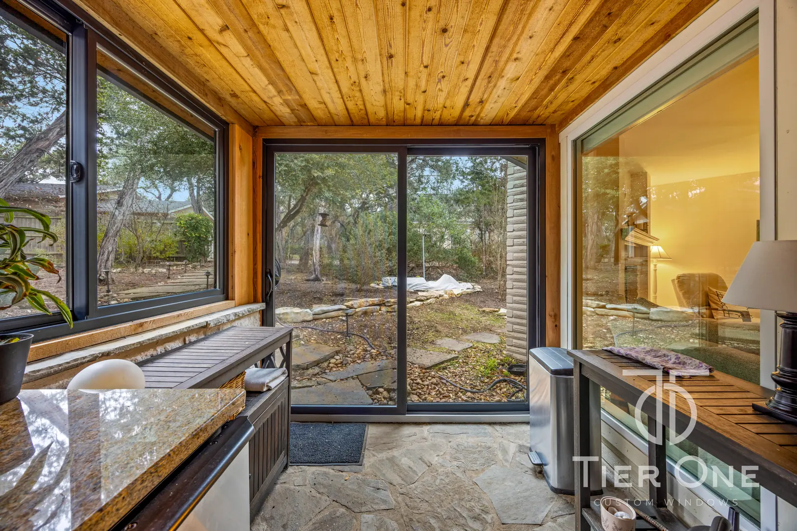 Bronze-framed sliding door and corner windows beside a porch kitchenette