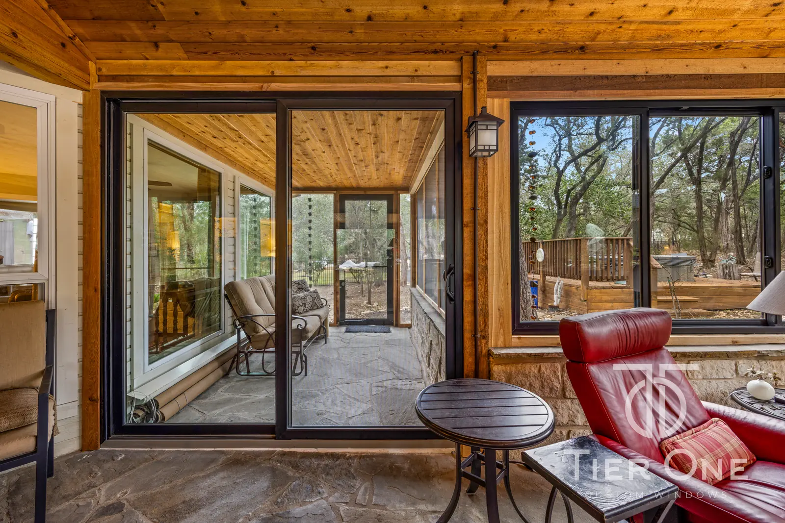 Bronze-framed sliding glass door between a stone porch and a screened room