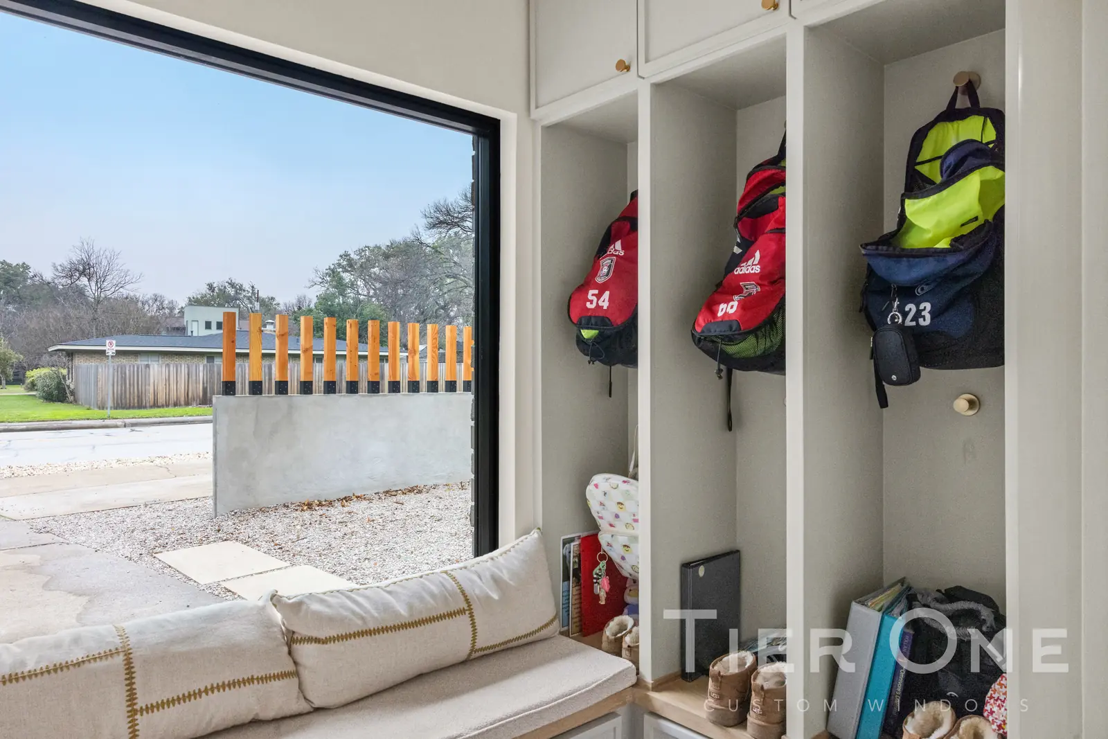 Black-framed picture window above a built-in bench seat in a mudroom