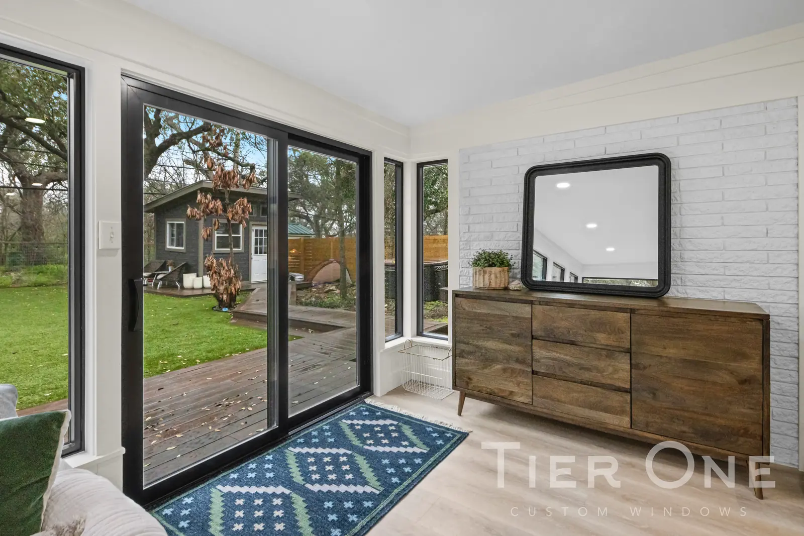Black-framed sliding patio door and corner window opening a room onto a wooden deck