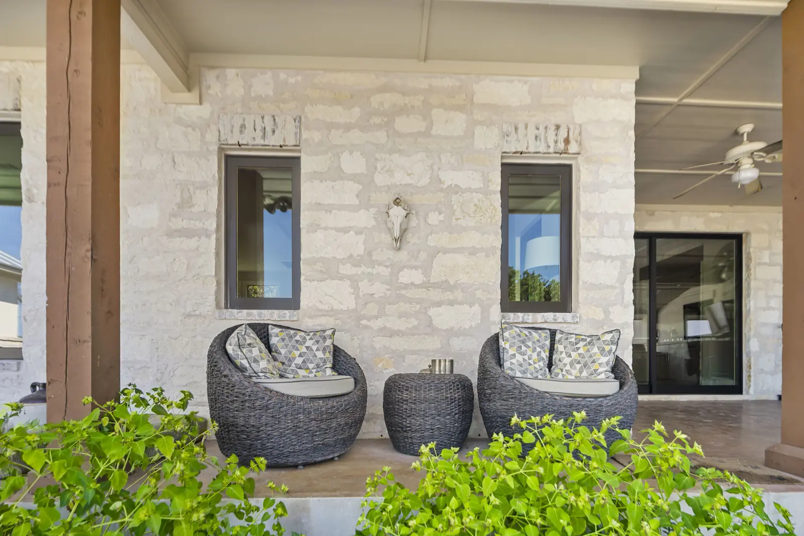 Bronze-framed windows and a sliding door beneath a stone covered porch